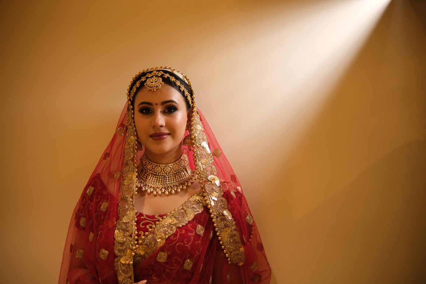 Bride in red and gold bridal lehenga with traditional jewellery
